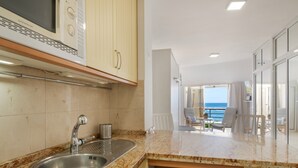 A kitchen with a stainless steel sink, a microwave, and a view of the balcony. - Vacation Studio 'Primera Linea' with Sea View, Balcony and Wi-Fi (Las Palmas de Gran Canaria)
