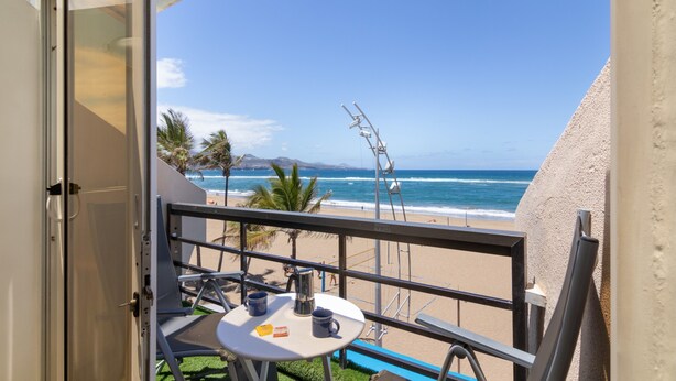 A balcony with a table, chairs, and a view of the beach and ocean. - Vacation Studio 'Primera Linea' with Sea View, Balcony and Wi-Fi (Las Palmas de Gran Canaria)