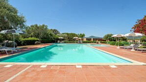 A swimming pool with lounge chairs and umbrellas, surrounded by greenery and a clear sky. - Holiday Home 'Casa Con Giardino' with Sea View, Wi-Fi and Air Conditioning (Porto Rotondo)