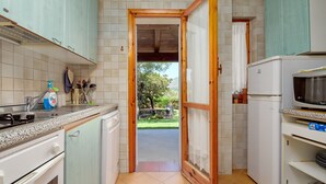A kitchen with a view to the outside, a microwave, and a refrigerator. - Holiday Home 'Casa Con Giardino' with Sea View, Wi-Fi and Air Conditioning (Porto Rotondo)