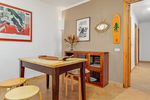 Un coin repas avec une table et des chaises en bois, un meuble avec une porte en verre et des œuvres d’art accrochées au mur.