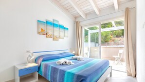 A bedroom with a bed, a nightstand, a window with a view, and a balcony. - Holiday Home 'Romantica Casa Al Mare' with Shared Pool, Wi-Fi and Air Conditioning (Viddalba)
