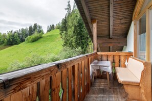 A wooden balcony with a table and bench, overlooking a green hillside. - Apartment 'Mittermüller Eibisch' with Shared Terrace, Balcony and Wi-Fi (Velturno)