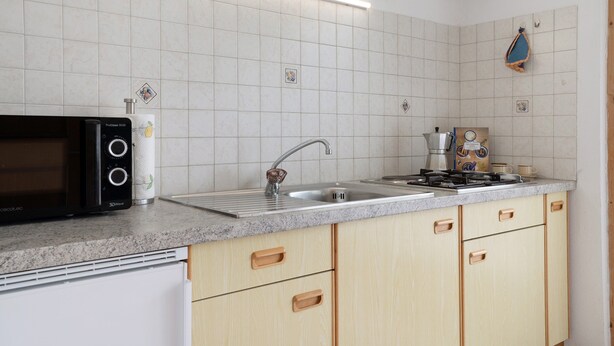 A kitchen with a microwave, sink, stove, and cabinets.