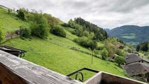 Paisatge rural amb una tanca de fusta, una construcció petita i cases amb teulades inclinades.