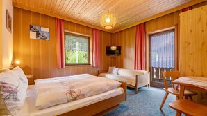 Una habitación de cabaña de madera con dos camas, un televisor, una mesa y una silla.