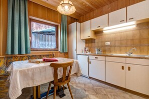 Cucina con mobili in legno, lavello e tavolo con una sedia.