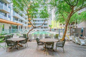 A poolside area with outdoor seating and a view of a multi-story building. - CDT PHX Apt Balcony Gym Pool WD & Parking (Phoenix)
