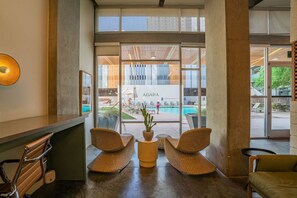A reception area with a pool view, wicker chairs, and a potted plant. - CDT PHX Apt Balcony Gym Pool WD & Parking (Phoenix)