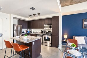 A modern kitchen with dark cabinets, stainless appliances, and a granite countertop. - CDT PHX Apt Balcony Gym Pool WD & Parking (Phoenix)