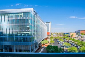 A modern building with a glass facade and a parking lot with multiple cars.