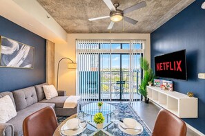 A living room with a sofa, coffee table, and a TV displaying 'NETFLIX'. - CDT PHX Apt Balcony Gym Pool WD & Parking (Phoenix)