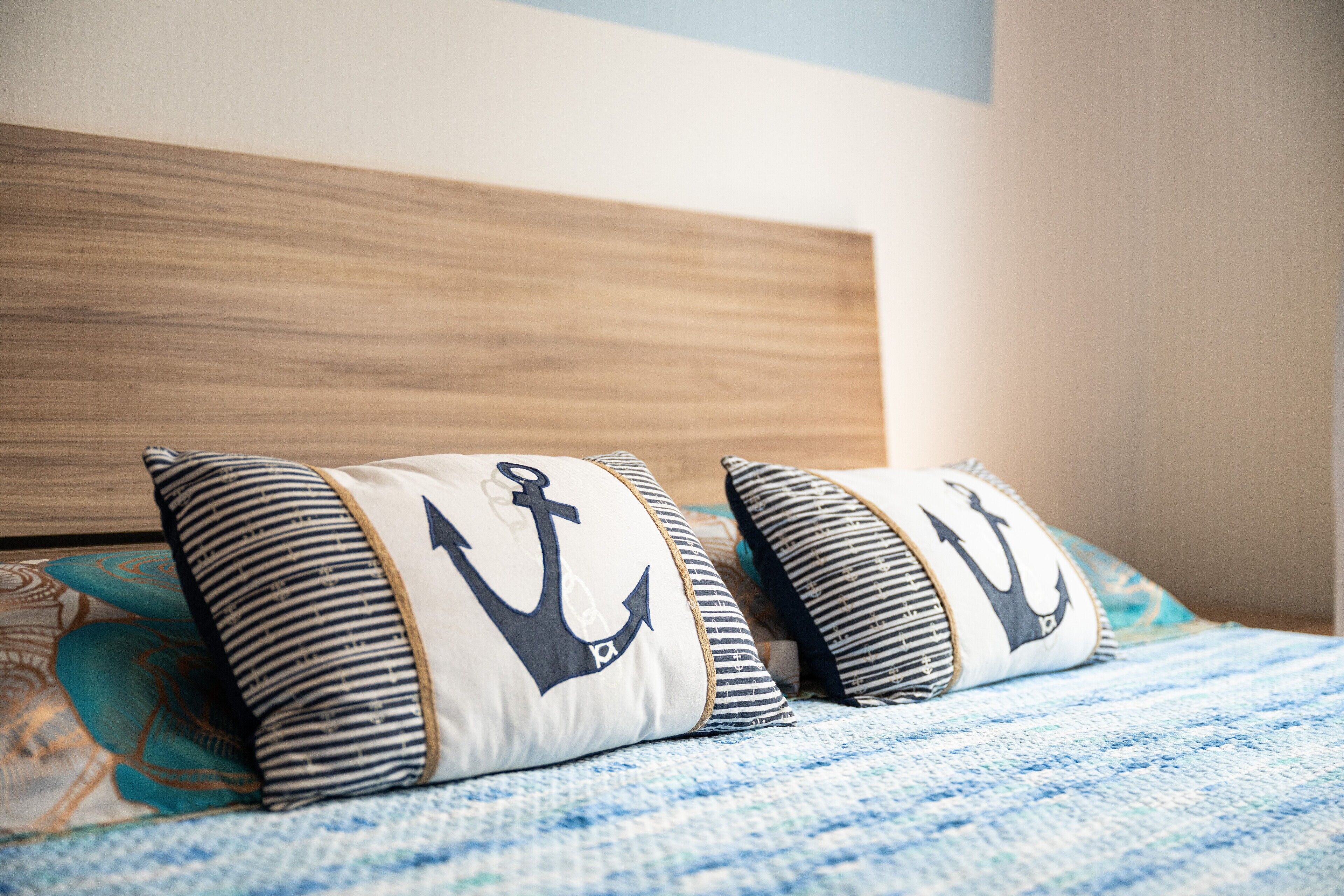 Un lit avec des oreillers à rayures et une couverture bleue.