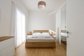 Un dormitorio moderno con una cama de madera, mesitas de noche, un espejo y una lámpara en el techo.