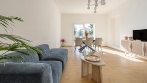 Un salon moderne avec un canapé gris, une table basse en bois et un téléviseur posé sur un meuble.
