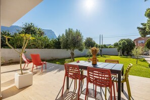 Eine Terrasse im Freien mit Tisch und Stühlen, einem Blumentopf und Blick auf einen Berg.