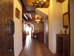 Ein Korridor mit einer Holztür, einer Steinwand und einem Essbereich mit Tisch und Stühlen.