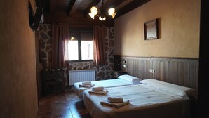 Una habitación con dos camas, una pared de piedra, una ventana con cortinas, un radiador y un techo de madera.