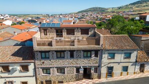 Un edificio de varios pisos con fachada de piedra, un balcón y vistas a un pueblo.