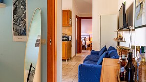 Une pièce comprenant un lit, un canapé, une armoire en bois et une planche de surf appuyée contre le mur.