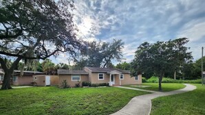 A residential area with a house, a curved sidewalk, and a grassy lawn.
