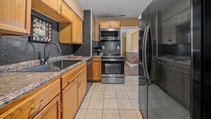 A modern kitchen with wooden cabinets, stainless steel appliances, and a granite countertop.