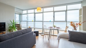 Une chambre d’hôtel moderne dotée d’une grande fenêtre, d’un canapé, d’un lit, d’une table à manger et d’un téléviseur.