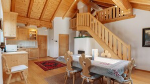 A wooden interior with a dining table, chairs, a staircase, and a kitchen area.