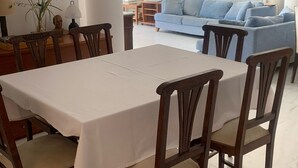 Un área de comedor con una mesa y sillas, un sofá y un jarrón con flores.