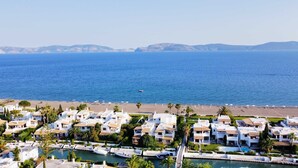 A coastal residential area with white buildings, a beach, and a marina. - Villa 'Beach , Swimming Pool For 8' with Sea View, Wi-Fi and Air Conditioning (Thermisia)