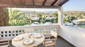 A covered outdoor dining area with a table set for four, overlooking a pool and a mountainous landscape. - Villa 'Beach , Swimming Pool For 8' with Sea View, Wi-Fi and Air Conditioning (Thermisia)