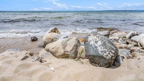 Une plage avec des rochers et du sable, un ciel dégagé et une eau calme.