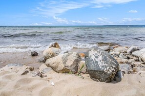 A beach with rocks and sand, a clear sky, and calm water. - 🏖️ Stylish The Shores Condo | Private Beach w/ Views ➠ 5716 (Acme)