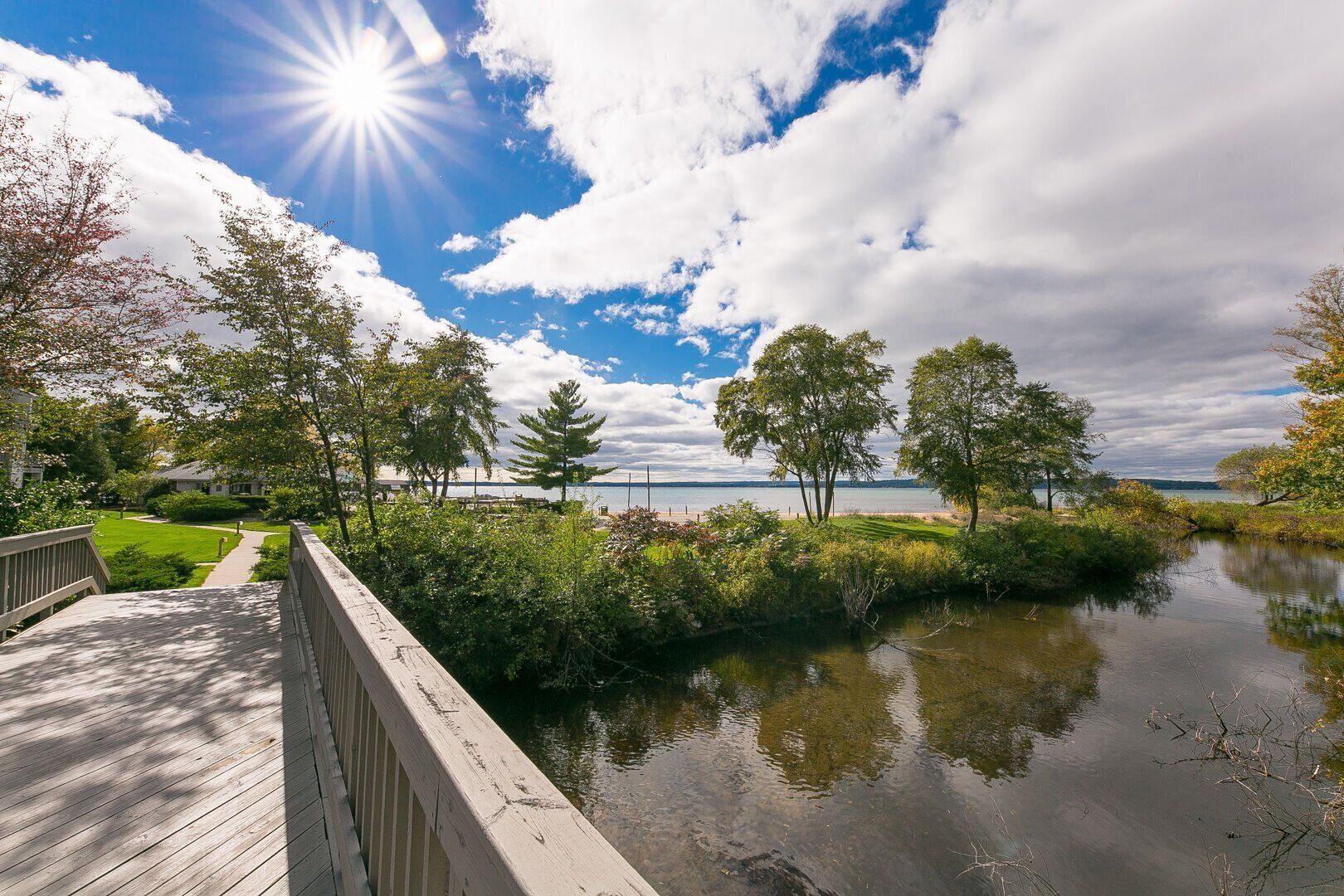 A wooden deck overlooking a calm lake with trees and a clear sky.