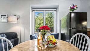 Une table à manger avec une bouteille de vin, un bol de collations et un vase de fleurs.