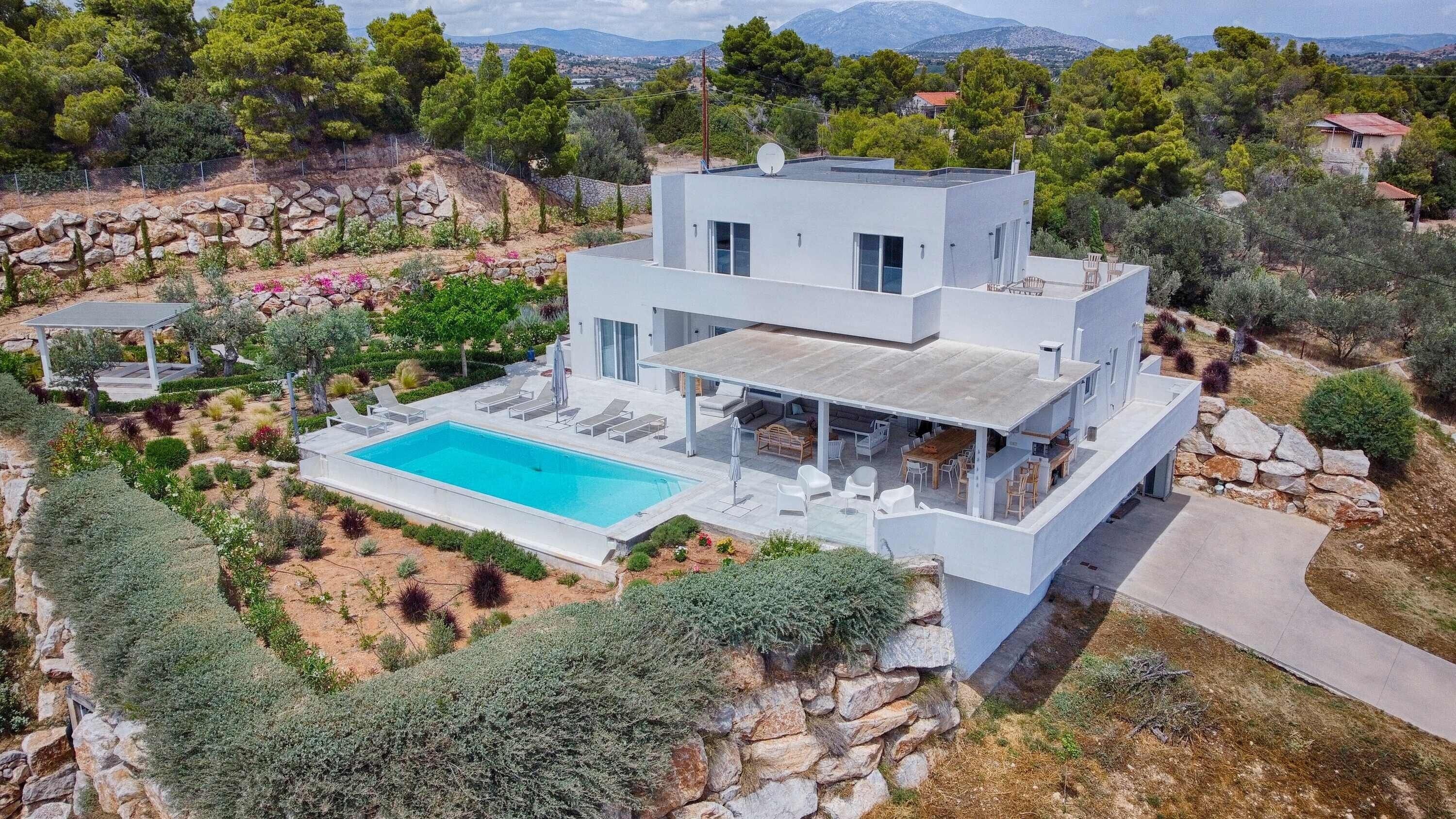 Ein modernes, zweistöckiges Haus mit Swimmingpool, Außenbereich und Blick auf die umliegende Landschaft.