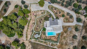 Vue aérienne d’une propriété comprenant une piscine, un grand bâtiment et des jardins aménagés.