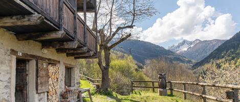 Un edificio rústico de madera con fachada de piedra, un balcón de madera y vistas a un paisaje montañoso.