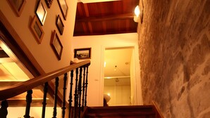 A wooden staircase with a handrail, leading to a room with a stone wall and framed pictures on the wall. - Holiday Home 'O Lar De Natalio' with Sea View, Private Terrace and Wi-Fi (RIANXO)
