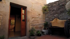 A stone building with a wooden door, potted plants, and a bench. - Holiday Home 'O Lar De Natalio' with Sea View, Private Terrace and Wi-Fi (RIANXO)
