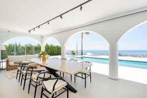 Een modern terras buiten met zwembad en uitzicht op zee.