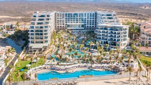 A hotel with a large pool surrounded by palm trees and lounge chairs. - Deluxe Ocean View Studio in Cabo, Villa la Valencia Resort (San José del Cabo)