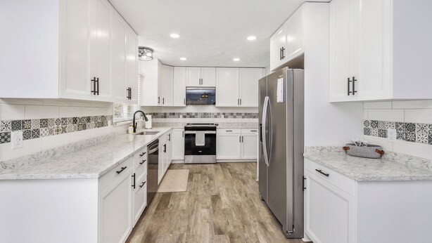 A modern kitchen with white cabinetry, a stainless steel refrigerator, and a built-in oven.