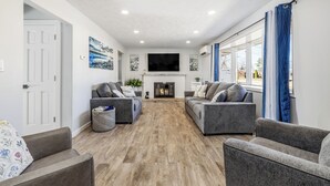 A living room with two grey sofas, a fireplace, and a flat-screen TV mounted above it.