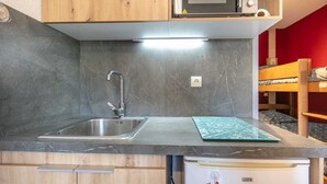 A kitchenette with a stainless steel sink, a microwave, and a built-in oven. - Lovely 4-person studio flat on the top floor with lift (Chamrousse)