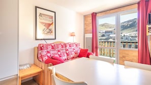 A room with a white table, red patterned sofa, and a framed picture on the wall.