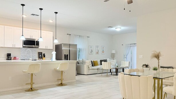 A modern kitchen with white cabinets, stainless steel appliances, and pendant lighting. - 3BR | Spacious | Entire House | Close to all Parks (Orlando)