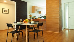 A modern kitchen with wooden cabinets, a dining table with chairs, and a fruit bowl on the table. - Torre Sevilla by The Local Way (Mexico City)