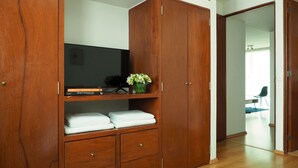 A wooden wardrobe with shelves, a flat-screen TV, and a vase with flowers. - Torre Sevilla by The Local Way (Mexico City)