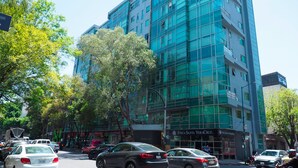 A modern building with a glass facade, multiple floors, and a commercial ground level with visible signage. - Torre Sevilla by The Local Way (Mexico City)